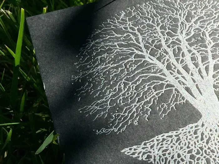 Silent Season silver tree print on a black sleeve in grass